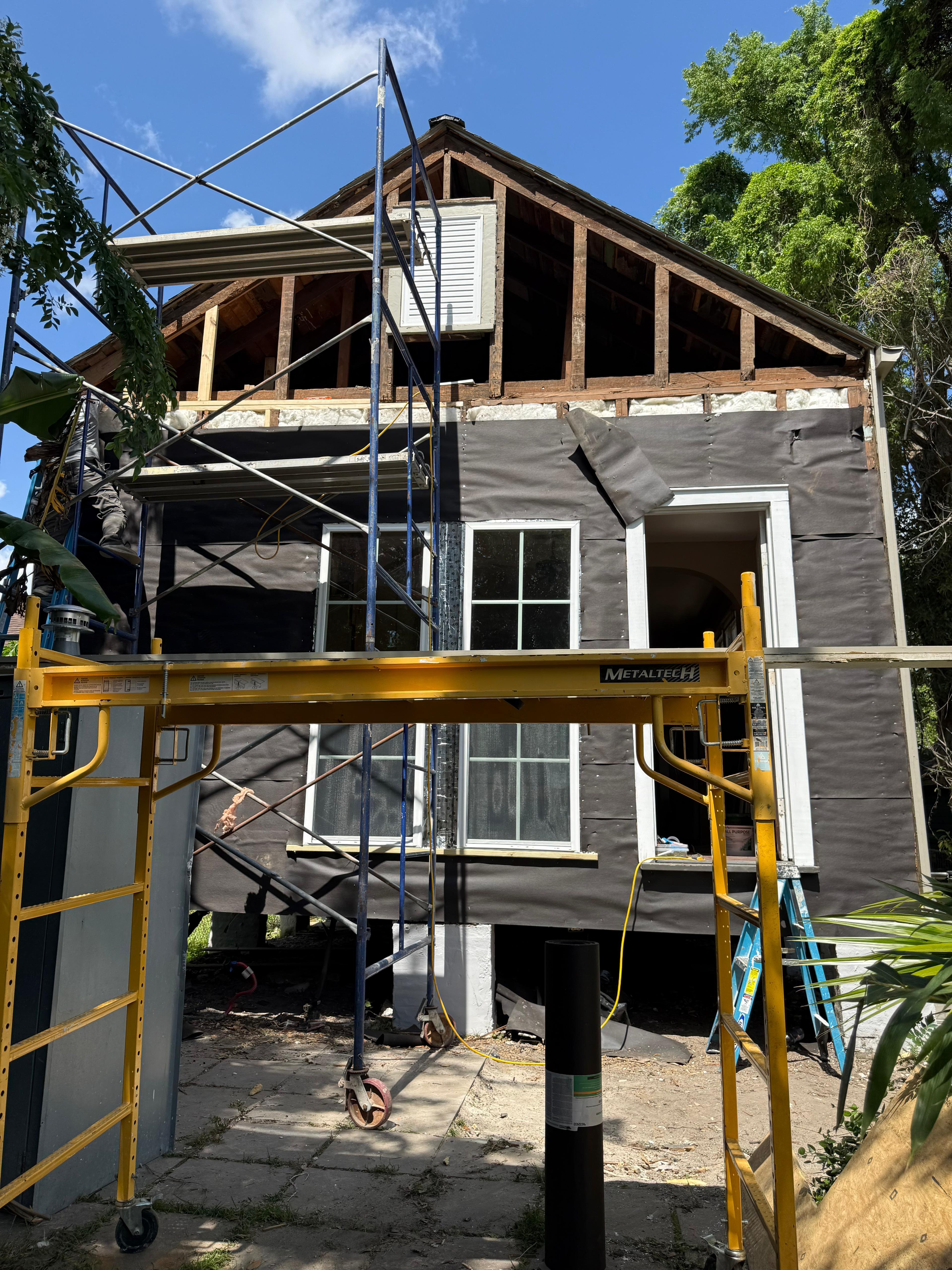 Exterior home renovation in progress, scaffolding and siding work, Southeast Louisiana